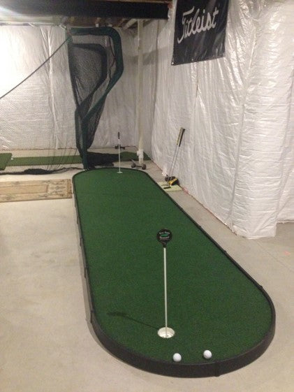 small indoor putting green in golf room next to hitting net